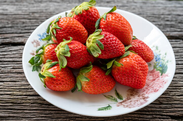 Many strawberries in a plate on a wooden table