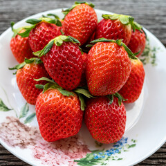 Many strawberries in a plate on a wooden table