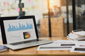 Documents with analytics data lying and laptop on table office workplace. 