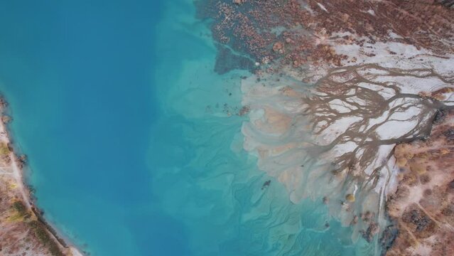 Divorces from rivers flowing into a mountain lake. It was as if the surface of the water was painted with watercolor from turquoise to dark blue gradient. There are autumn trees Top view of Lake Issyk