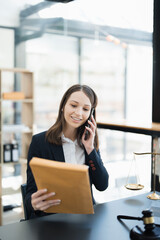 Portrait of a Asian woman lawyer studying lawsuit a for a client using smartphone , documents and...