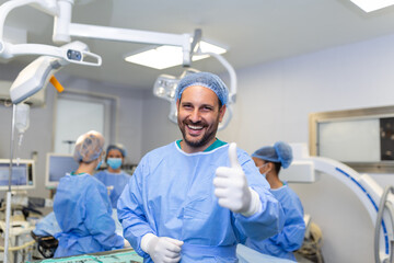 Young male surgeon standing in operating room showing thumbs up, ready to work on a patient. Male...