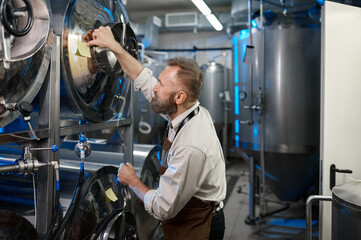 Male brewer making notes on the tanks during brewing process