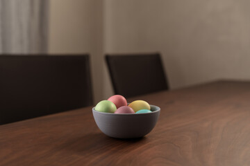 Easter eggs in a bowl with napkin on walnut wood table with copy space