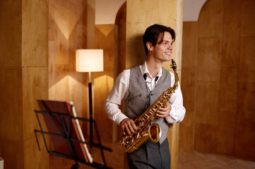 Jazz musician playing saxophone and leaning against art studio wall