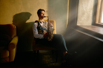 Jazz musician playing saxophone front of window © Nomad_Soul