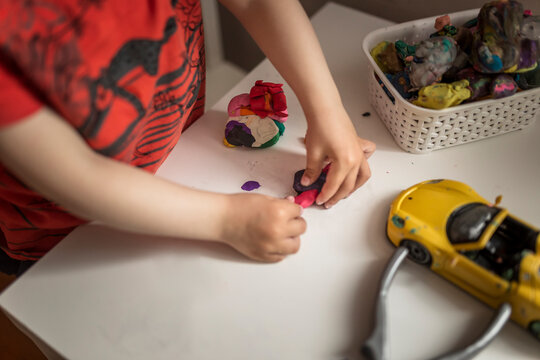 Hands Of A Child Playing With Play Doh On White Table