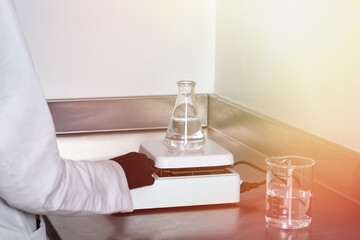 scientific chemist in laboratory next to Magnetic Stirrer and flask