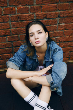 Portrait of girl in jeanscoat sits on a baseball court