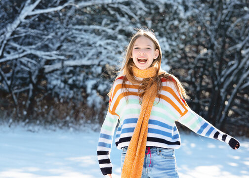 Happy teen girl with yellow scarf outdoors in the snow.