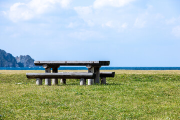 海辺の芝生に置かれた古びた木のベンチとテーブル