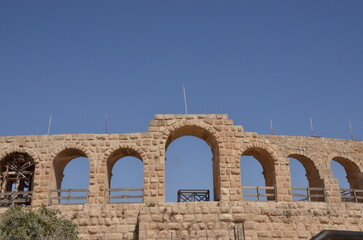 Fototapeta premium Sunny temples, arches, the Nymphaeum, stone ornaments, columns and column bases on the ruins of the city of Jerash in Jordan.