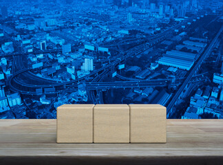 Three wood block cubes on wooden table over modern city tower, street, expressway and skyscraper