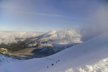Climbing tourists in winter to the peak of a mountain peak
