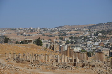 Sunny temples, arches, the Nymphaeum, stone ornaments, columns and column bases on the ruins of the city of Jerash in Jordan.