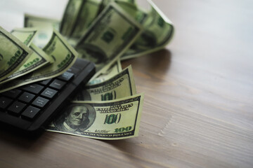 Computer keyboard and a scattering of 100 dollar bills on the table. The work of a programmer and blogger on the Internet.