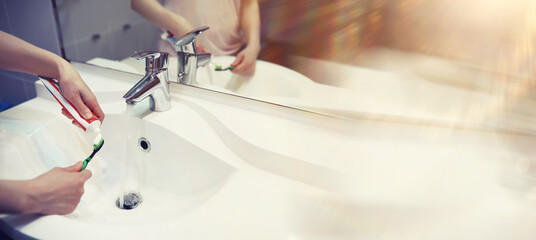 Tooth brush and paste with mirror background in the bathroom. Close up of toothpaste and toothbrush. Hands squeezing whitening paste on brush, taking care about mouth hygiene.