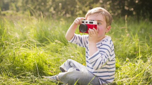 Little boy takes photo with toy camera in the park