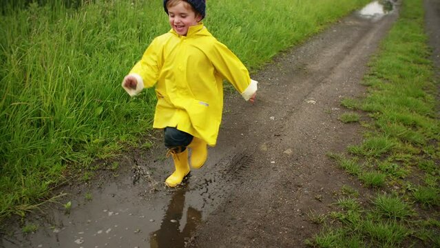 Young boy running through puddle after rain in slow motion