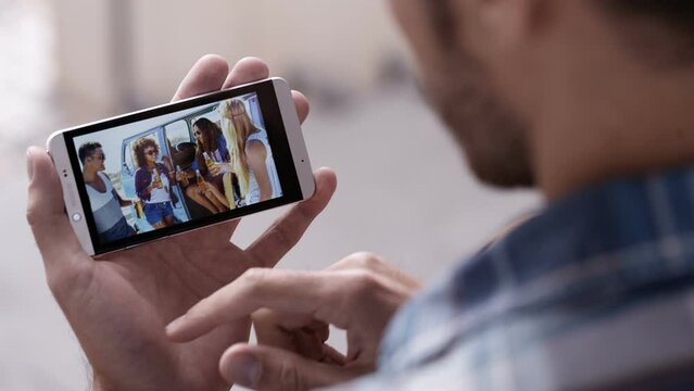 Man uses smartphone to look at photos of his friends together