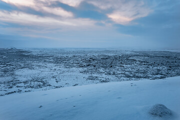 Iceland snow covered vulcanic area in winter with cloudy blue yellow sky