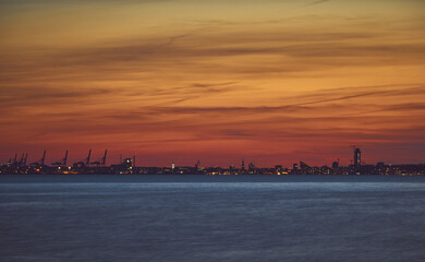 Fototapeta na wymiar Skyline der Stadt Aarhus zum Sonnenuntergang mit der Ostsee im Vordergrund und orangenem Himmel