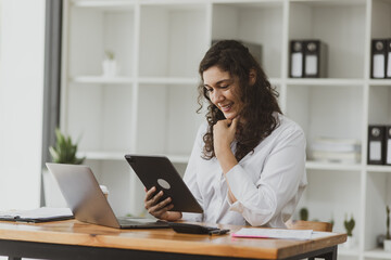 Obraz premium Businesswoman using tablet and laptop computer working at desk in office.