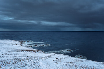 Iceland storm over the ocean with cloudy sky and snow coastline