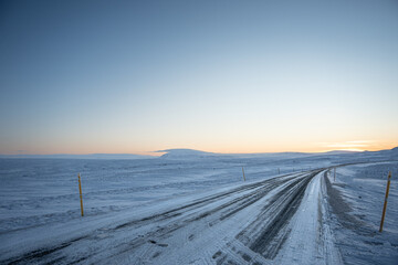 Iceland sunset or sunrise with clear blue yellow sky over winter snow road landscape