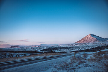 Fototapeta na wymiar Iceland road with snow covered mountains in winter sunset with blue sky