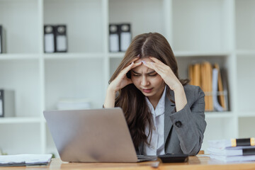 Young businesswoman are stressed and tired from work sitting at desk in the office, feeling sick at work, stress from work.	