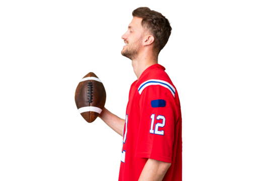 Young caucasian man playing rugby over isolated chroma key background laughing in lateral position