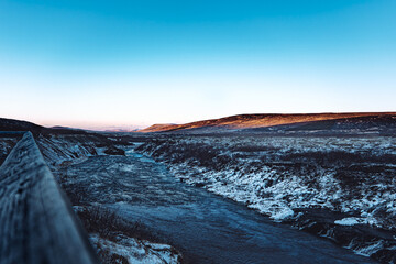 Iceland Hraunfossar clear orange sunrise over mountain landscape with river waterfall in winter
