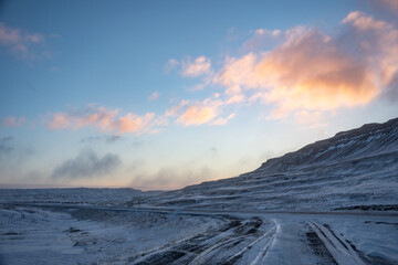 Iceland sunrise or sunset with blue sky in winter over road with snow covered mountain