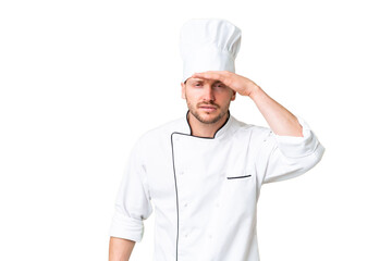 Young caucasian chef over isolated chroma key background looking far away with hand to look something