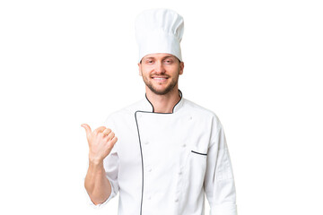 Young caucasian chef over isolated chroma key background pointing to the side to present a product