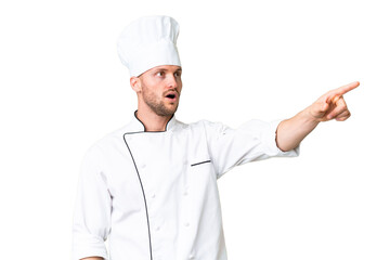 Young caucasian chef over isolated chroma key background pointing away