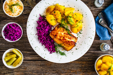 Fried pork loin with boiled potatoes and red cabbage on wooden table
