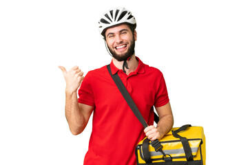 Young delivery man with thermal backpack over isolated chroma key background pointing to the side to present a product