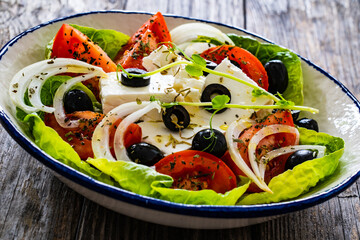 Fresh vegetable salad with feta cheese on wooden table
