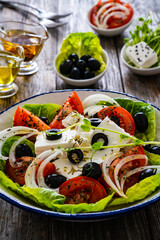 Fresh vegetable salad with feta cheese on wooden table
