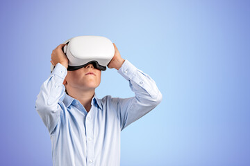 Child boy standing with vr glasses headset on copy space blue ba