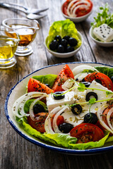 Fresh vegetable salad with feta cheese on wooden table
