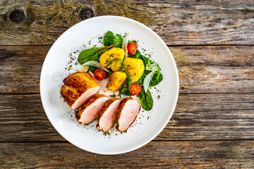 Fried pork loin with fried potatoes and vegetables on wooden table
