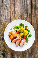 Fried pork loin with fried potatoes and vegetables on wooden table
