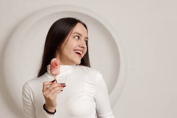 Indoor portrait of positive smiling brunette young woman on white background holding sweet dessert cake in hands.