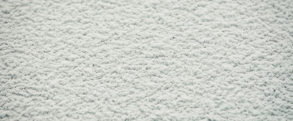 Minimalist nature background with white snow on flat surface. Snow-covered frozen windshield. Minimal winter backdrop with snowbound glass of car close up. Natural large snow grains on windscreen.