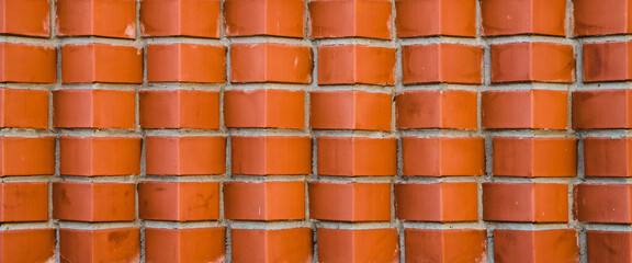 Individual design of red brick wall from diagonally angular bricks close up. Geometric background with brown horn bricks in rows close-up. Minimal backdrop with vivid bricks pattern of original form.