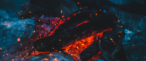 Vivid smoldered firewoods burned in fire closeup. Atmospheric background with orange flame of...