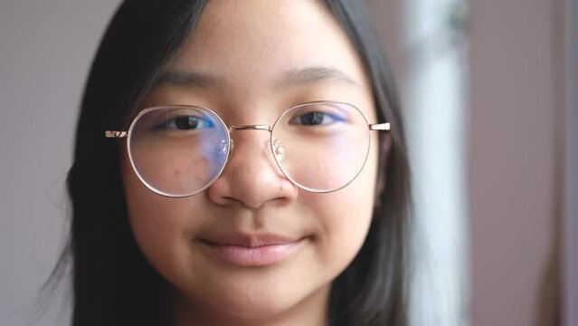 Asian girl wearing eyeglasses smiling brightly showing off her braces
